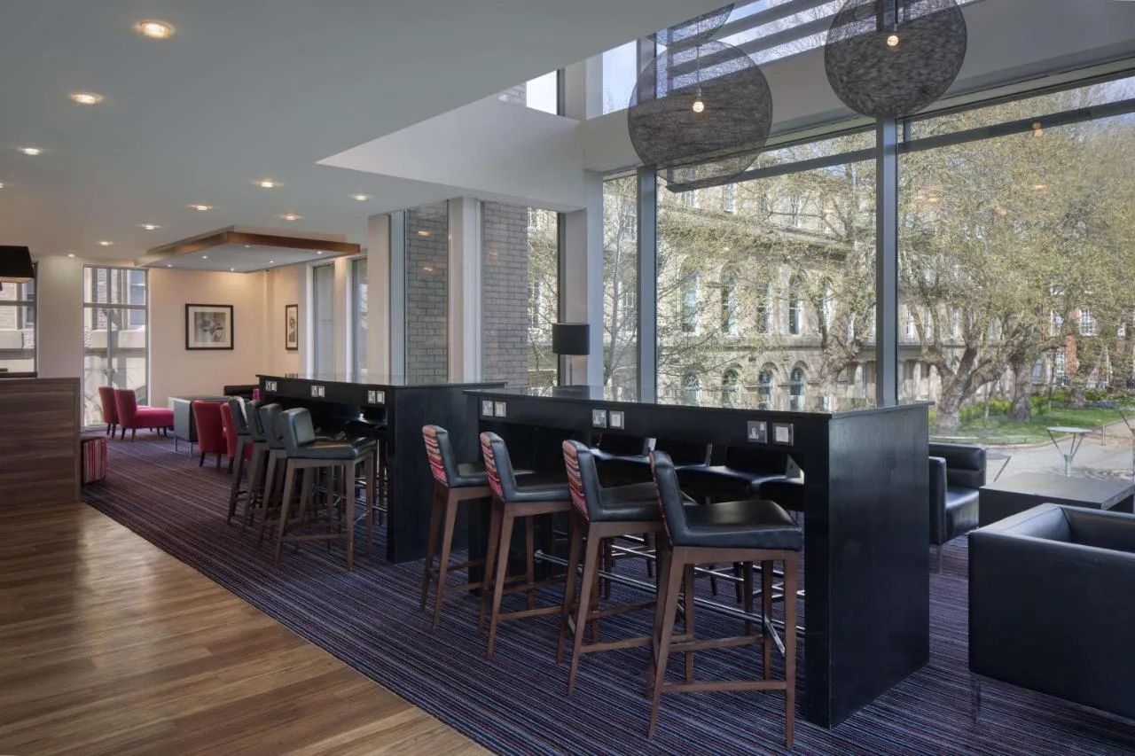 a lobby with a bar with chairs and tables at Hampton by Hilton York in York
